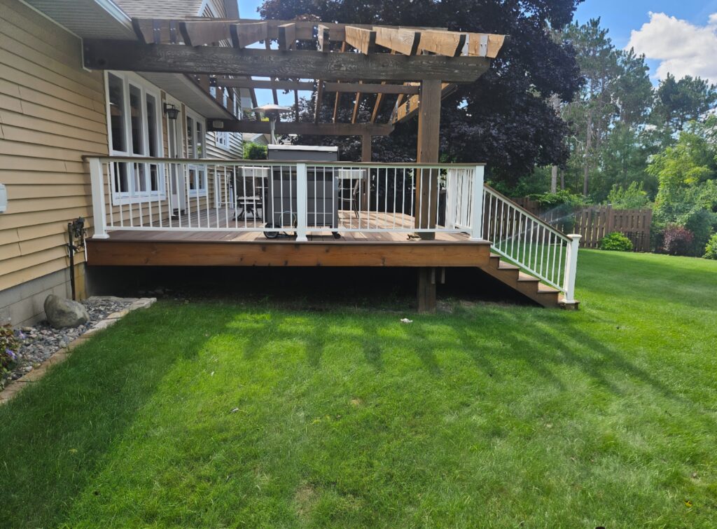 Deck with white railing, steps, and a timber pergola beside a house.